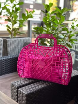Vibrant pink bag in a stylish outdoor setting. Modern fashion and design against a backdrop of greenery.