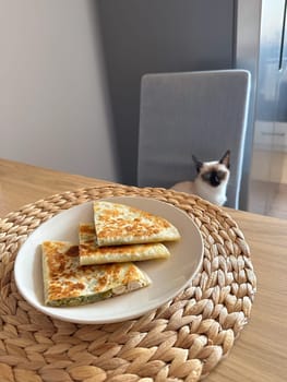 Plate of quesadillas on a woven mat with a cat in background. Simple yet inviting setup makes this image perfect for lifestyle and food-related content.
