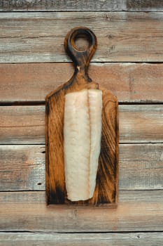 A clean, freshly sliced fillet of white fish rests on a handcrafted wooden cutting board