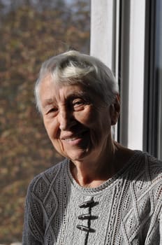 Portrait of elderly woman near window, Grandmother smiling