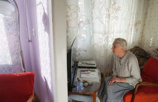 The poorly seeing senior woman watching tv at home.