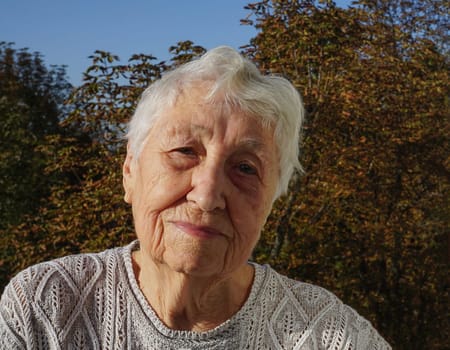 Portrait of beautiful senior woman posing in autumn park