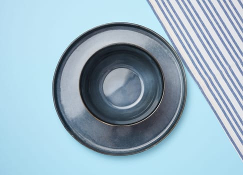 Round ceramic empty blue plates and blue striped kitchen towel, top view