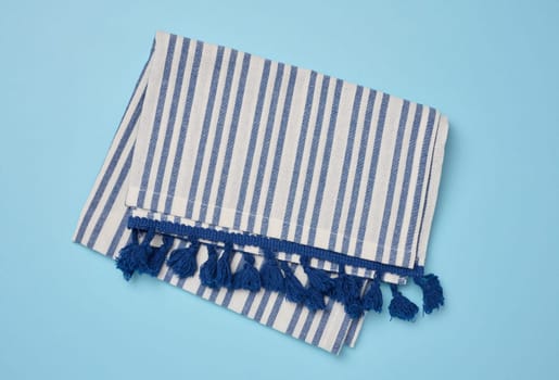 Folded linen striped kitchen towel on blue background, top view