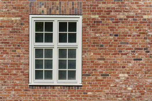 Window with white frame on a historic brick building in Germany