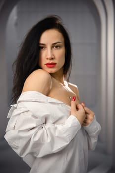Portrait of graceful and gorgeous woman with black hair and white oversized shirt
