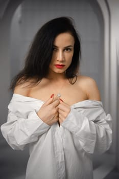 Moody portrait of cute young woman in oversized off-the-shoulder shirt
