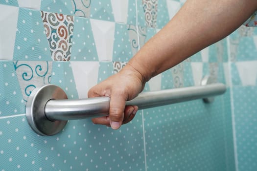 Asian elderly old woman patient use toilet support rail in bathroom, handrail safety grab bar, security in nursing hospital.