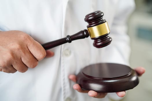 Asian doctor holding court hammer for and crime law justice, forensic medicine.