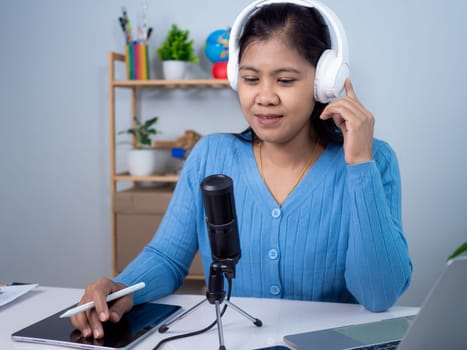 Woman talking into microphone on stand, Content creator concept,  Lead on-line communication, Discuss topic, looks at notebook screen, Engaged in streaming, Virtual meeting event, Podcast, Webinar.