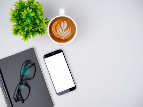 Top view of mock up modern workspace with blank screen smartphone, Coffee cup, Notebook, Pencil, Glasses. Office situation with keyboard and accessories isolated on white. Copy space, Flat lay.