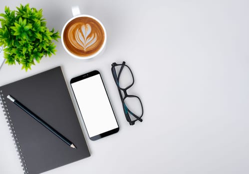 Top view of mock up modern workspace with blank screen smartphone, Coffee cup, Notebook, Pencil, Glasses. Office situation with keyboard and accessories isolated on white. Copy space, Flat lay.