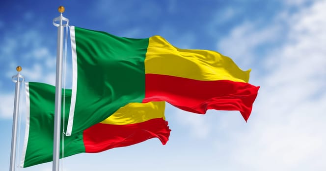 Two Benin national flags waving. Two horizontal yellow and red bands on the fly side and a green vertical band at the hoist. 3d illustration render. Fluttering fabric. Selective focus