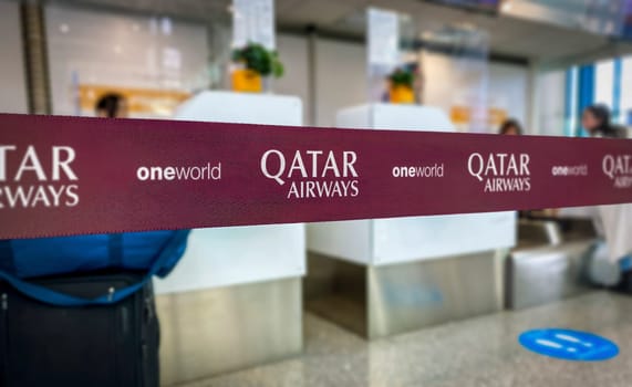 Doha, QA, May 22 2022  Close-up of Qatar Airways branded ribbon at an airport check-in counter. The visible logos include Qatar Airways and Oneworld alliance.