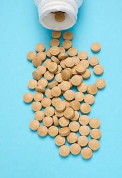 Yellow round pill for healthcare. Medical treatment, blue background, top view