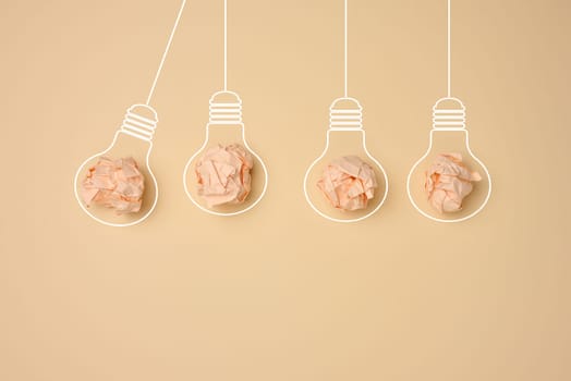 Crumpled balls of paper inside an electric lamp on a beige background. Concept of new ideas, brainstorming