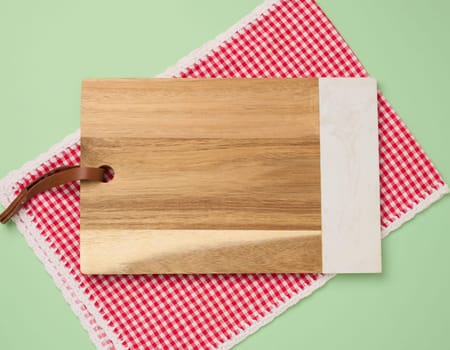 Empty rectangular wooden kitchen cutting board on green background, top view