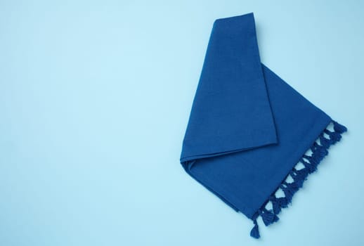 Folded blue kitchen towel on a blue background, top view. Copy space
