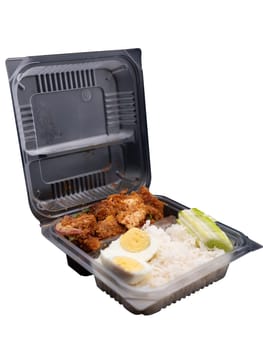 Spicy chicken rice salad with boiled eggs put in a clear plastic box.