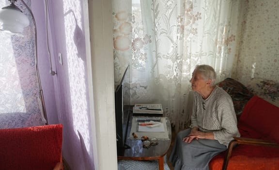 The poorly seeing senior woman watching tv at home.