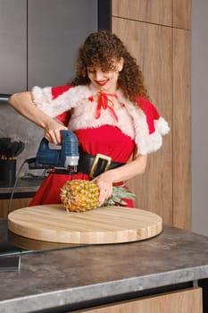 Grotesque and non-standard application of working tools in the kitchen. Woman cutting pineapple with jigsaw