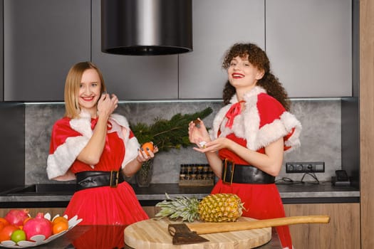 Two women in masquerade Christmas dress having fun in the kitchen