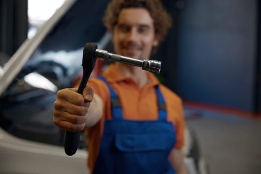 Closeup ratchet wrenches with fixed detail in hand of car mechanic selective focus. Auto technician advertising professional work and high quality service