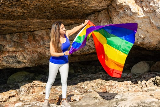 woman, middle aged, outdoors waving pride flag, concept of libertat, equality.