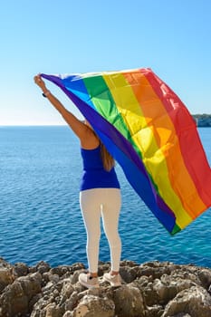 woman, middle aged, outdoors waving pride flag, concept of libertat, equality.