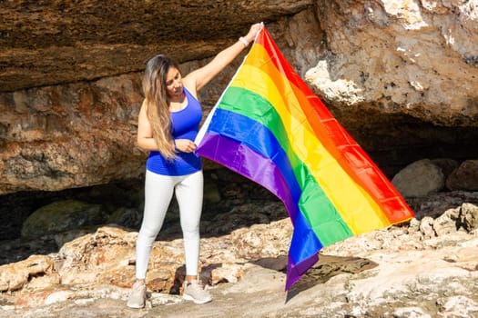 woman, middle aged, outdoors waving pride flag, concept of libertat, equality.