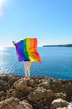 woman, middle aged, outdoors waving pride flag, concept of libertat, equality.