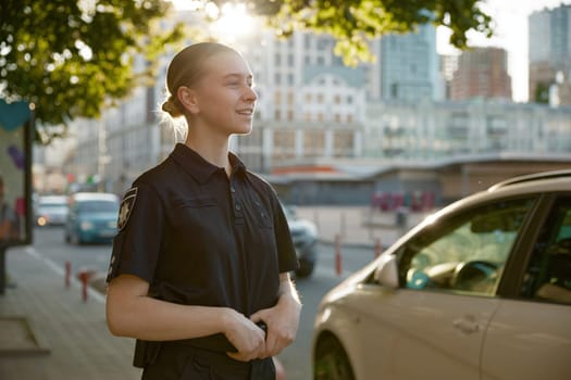 Closeup view of female patrol police officer standing on city street at daytime. Woman justice guardian at work