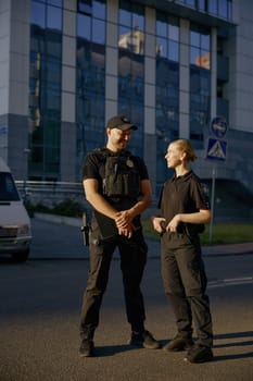 Nice conversation of to friendly smiling patrol officers standing at police station department outdoors