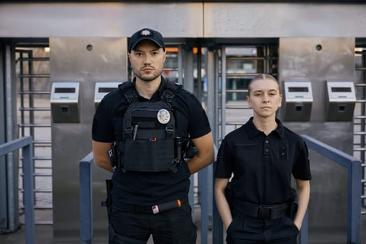 Diverse armed police officers wearing protective bulletproof vest patrolling and guarding entrance to public subway