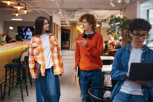 Three teenagers walking in modern office and discussing topical news. Young adults in coworking office