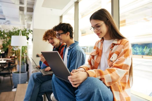 Teenagers working in office using their laptops. Guys working online. Young employees communicating with each other