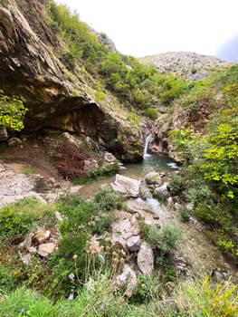 Serene waterfall cascades through a rocky canyon, surrounded by lush greenery and vibrant foliage. Tranquil scene invites contemplation and escape into nature untouched beauty.