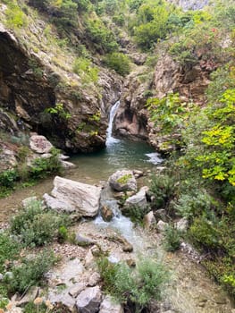 Serene waterfall cascades through a rocky canyon, surrounded by lush greenery and vibrant foliage. Tranquil scene invites contemplation and escape into nature untouched beauty.