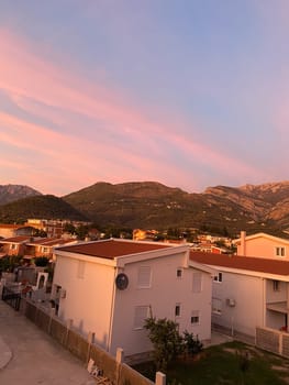 Vibrant sunset casts warm hues over residential buildings, creating a stunning contrast against evening sky. Peaceful transition from day to night, highlighting the serene beauty of urban life.