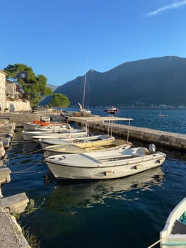Small wooden boat floats calmly in a serene harbor, tied to dock as gentle waves reflect surrounding landscape. Coastal life and tranquil maritime environments.
