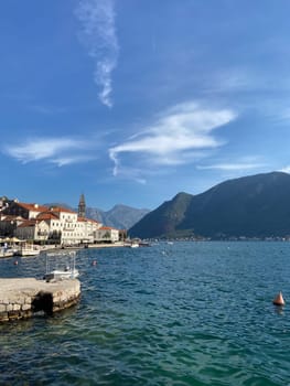 Coastal village nestled between majestic mountains and a serene sea under a clear blue sky. Scene captures the allure of tranquil coastal living and breathtaking natural scenery