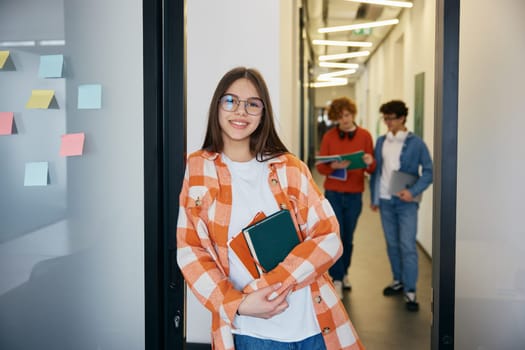 Attractive teenage girl in office holding work books. Smiling young worker enjoying her job