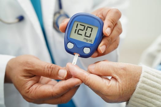 Asian doctor using digital glucose meter for check sample blood sugar level to treatment diabetes.
