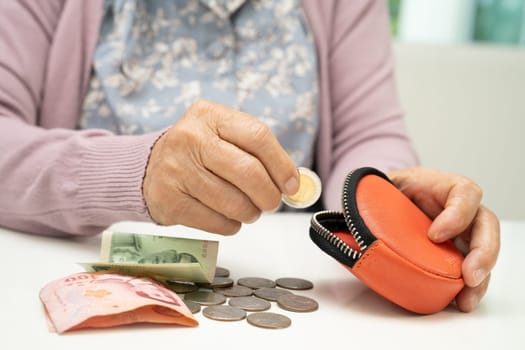 Asian senior or elderly old lady woman holding counting coin money in bag. Poverty, saving problem in retirement.