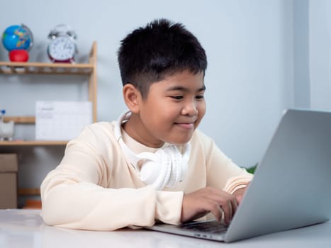 Educational of tech concept, Staying at home, Little Asian boy student using computer laptop learning.  Presenting a modern educational way of life. Virtual internet online class from school teacher.