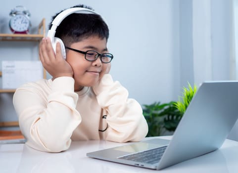 Asian student boy using headphones and computer learning. Educational of tech concept, Staying at home, Presenting a modern educational way of life. Virtual internet online class from school teacher.