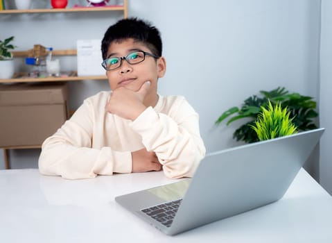 Asian student boy thinking using computer learning. Educational of tech concept, Staying at home, Presenting a modern educational way of life. Virtual internet online class from school teacher.