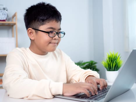 Educational of tech concept, Staying at home, Little Asian boy student using computer laptop learning.  Presenting a modern educational way of life. Virtual internet online class from school teacher.