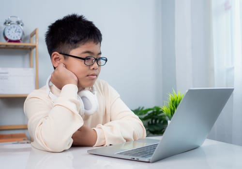 Educational of tech concept, Staying at home, Little Asian boy student using computer laptop learning.  Presenting a modern educational way of life. Virtual internet online class from school teacher.