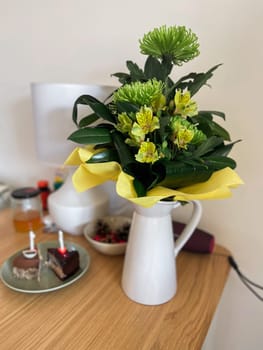Elegant yellow and green floral arrangement in white vase on table. Birthday concept.